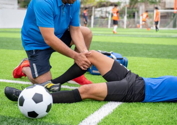 istockphoto-1025958882-612×612 Footballer wearing a blue shirt, black pants injured in the lawn during the race.