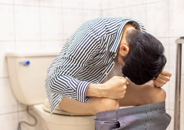 Young man feels uncomfortable in his stomach and is constipated in the toilet Young man feels uncomfortable in his stomach and is constipated in the toilet